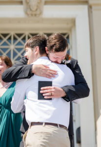 Groom and best friend hugging on the Elko Courthouse Steps
