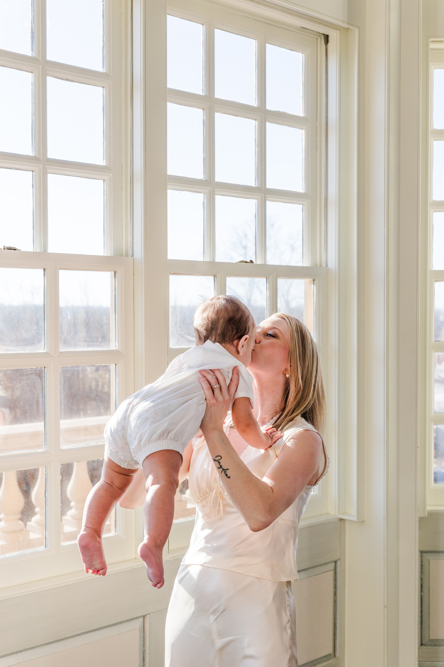 A mom holding her baby and kissing him, and an Elko Family Photographer capturing the image